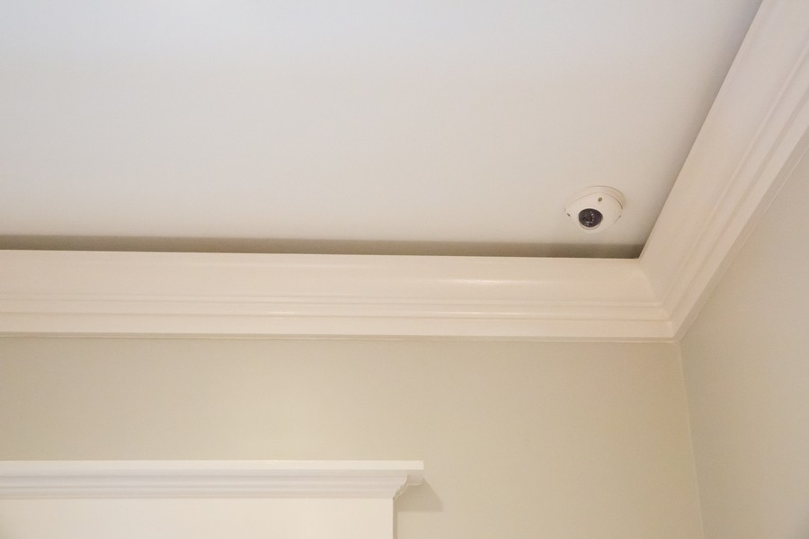 A dome security camera mounted on the corner of a ceiling in a Utah home.