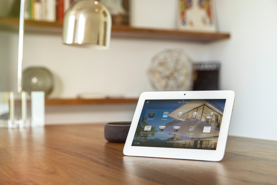 A smart home system touchscreen sits on a table top.