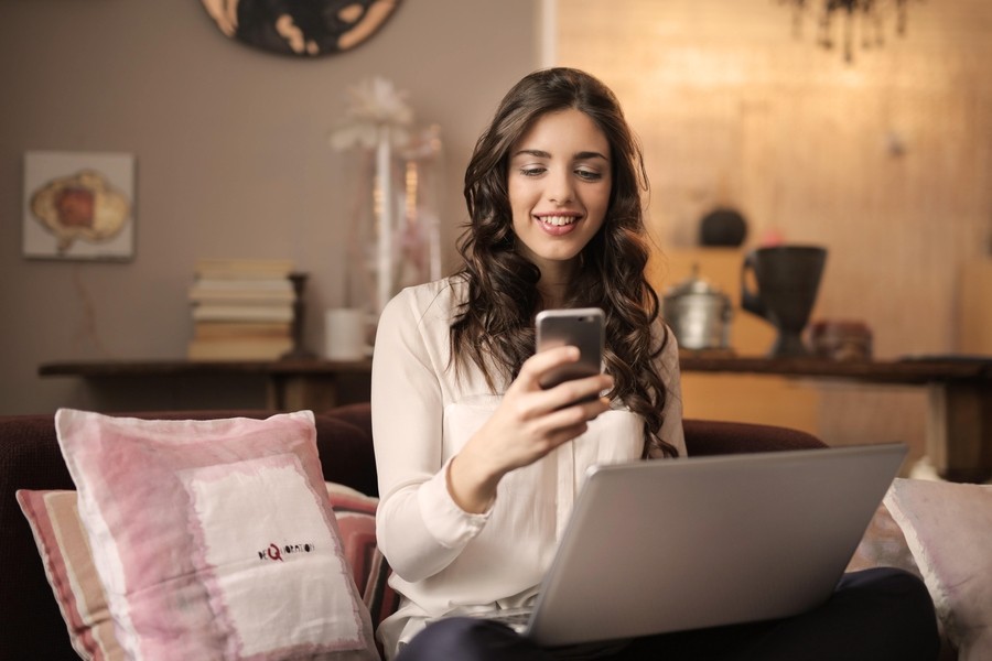 A woman working on a laptop and phone connected to a Wi-Fi network