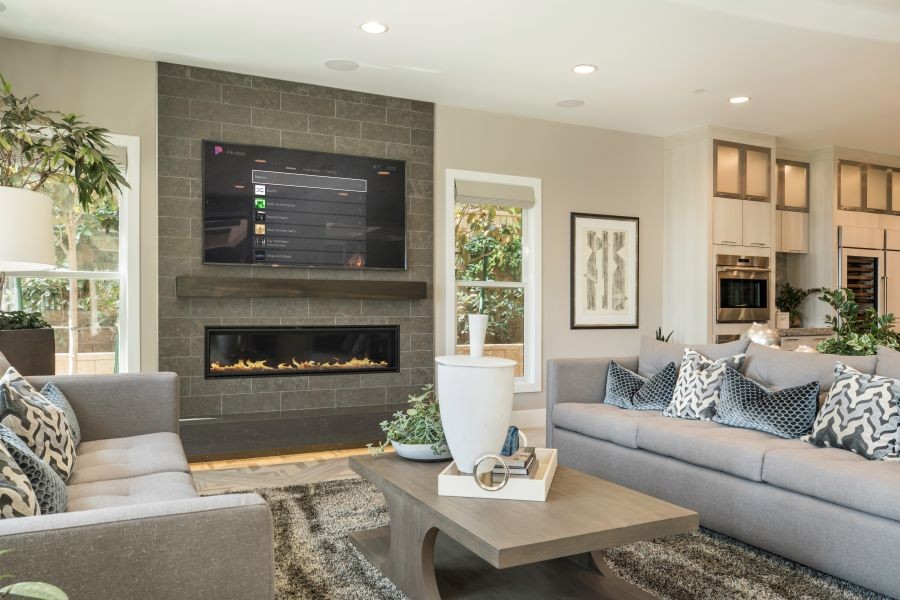 A living room with in-ceiling speakers and the Control4 operating system displayed on the TV screen.