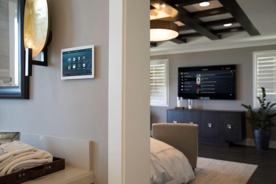  A home with an on-wall Control4 touchscreen and a Control4 platform displayed on the bedroom’s flatscreen TV