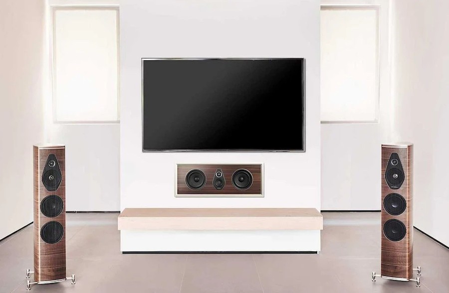 A set of speakers flanks a TV on a wall, with a flush-mounted center channel in-wall speaker matching the tower speaker finishes.